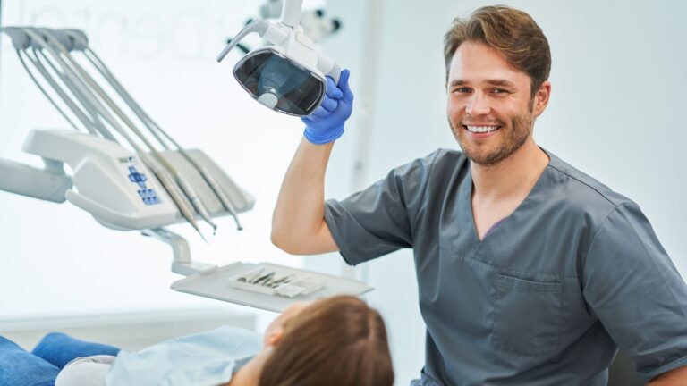 Dentista em bata clinica a segurar uma camera intraoral numa consulta dentaria
