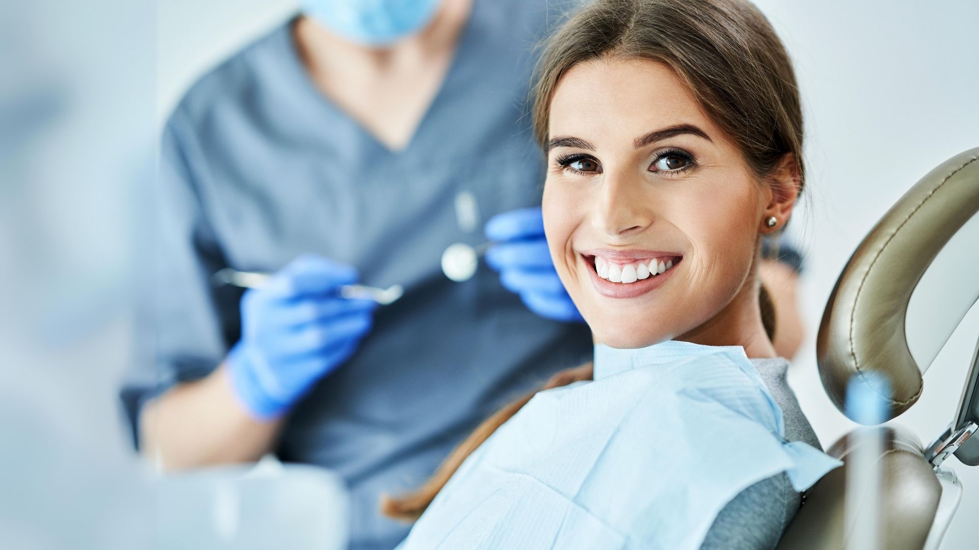Paciente adulta sorridente sentada numa cadeira dentária durante uma consulta