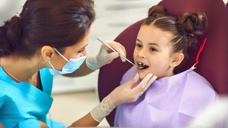 Dentista a examinar uma menina numa consulta de odontopediatria