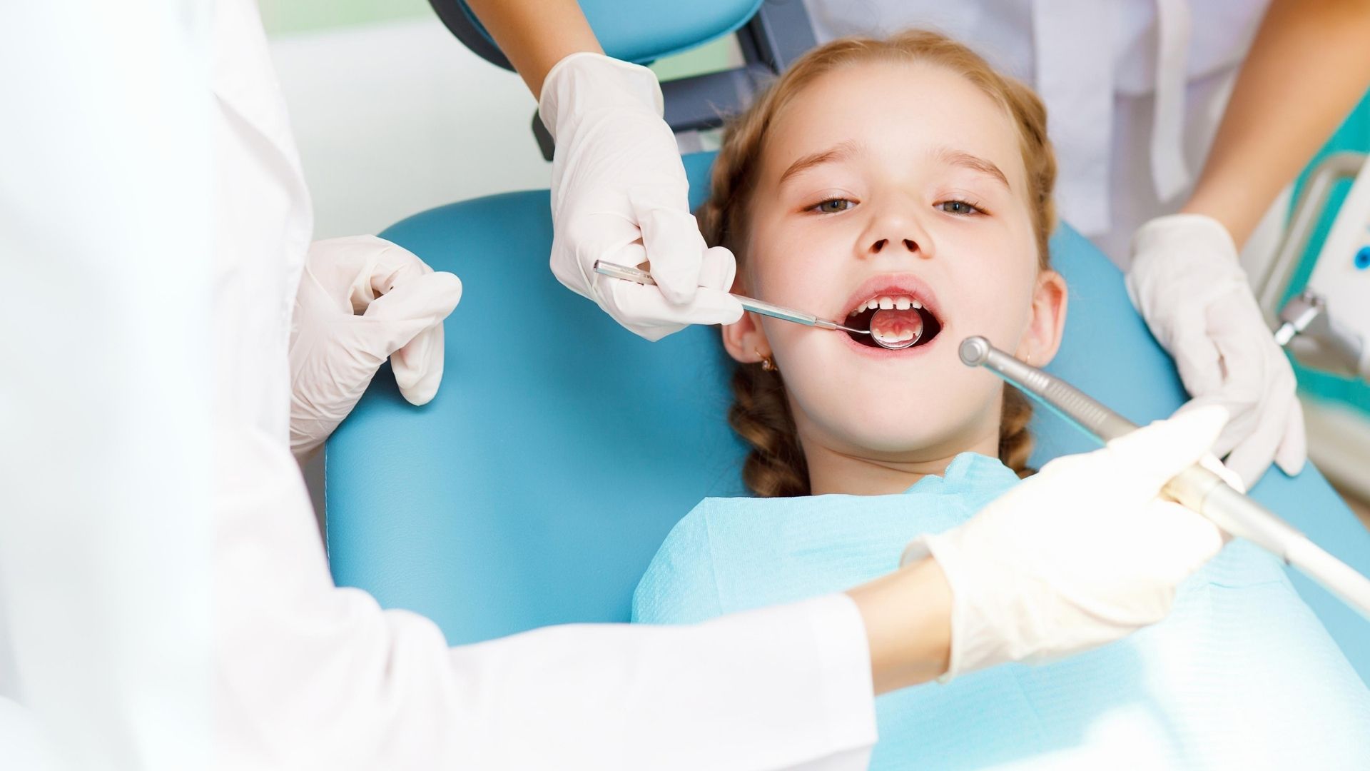 Dentista a examinar a boca de uma criança durante uma consulta