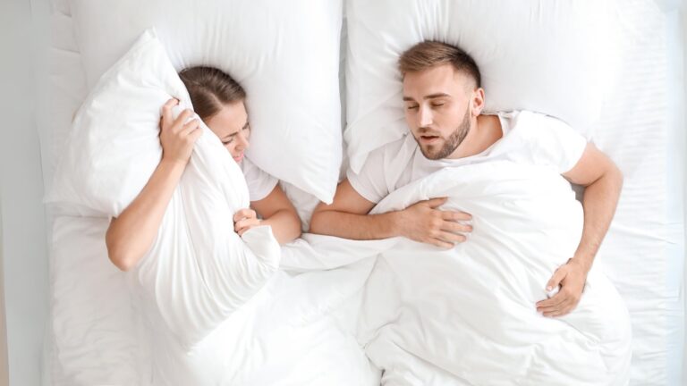 Casal a dormir numa cama com possível interrupção do sono