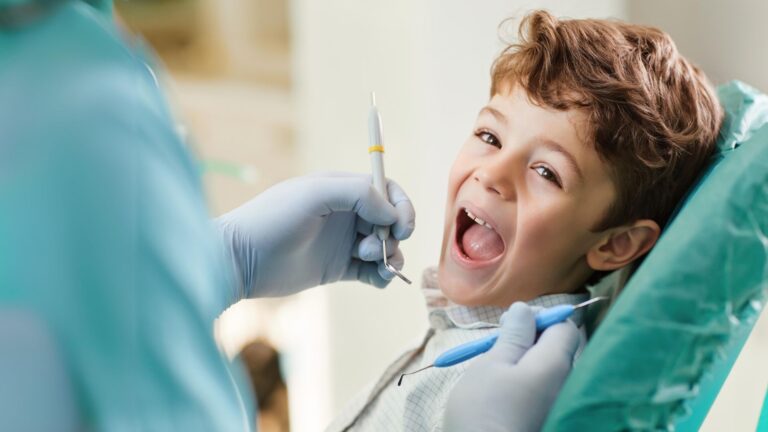 Menino sorridente durante uma consulta de odontopediatria