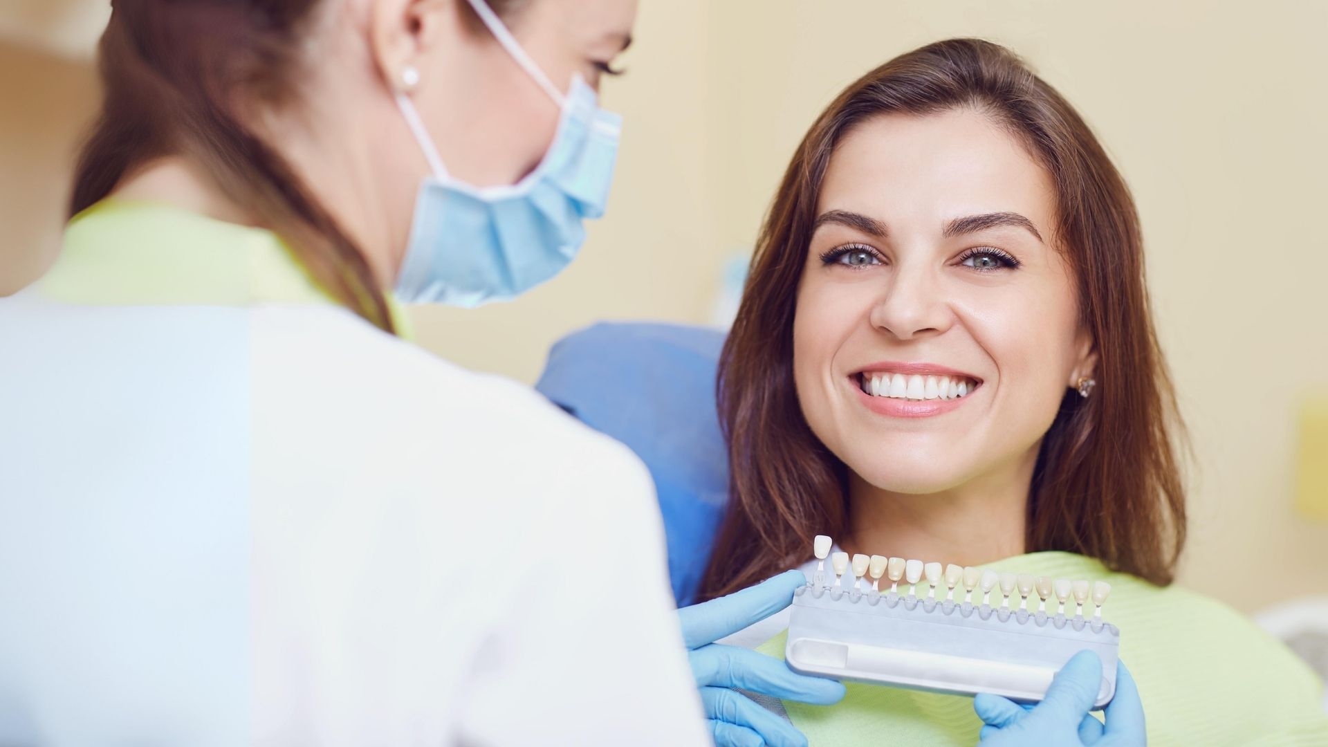 Mulher sorridente acompanhada por uma profissional que apresenta um modelo dentário